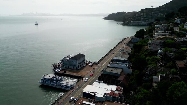Vista panor&aacute;mica al atardecer: Un dron vuela suavemente sobre los pintorescos barrios de San Francisco mientras el sol se pone, ba&ntilde;ando la ciudad en tonos dorados y rosados. Se destacan las t&iacute;picas ca
