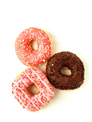 Three donuts stacked on top of each other with pink frosting and sprinkles. The donuts are piled high and look delicious. Internationally popular pastry product. Perfect desert.
