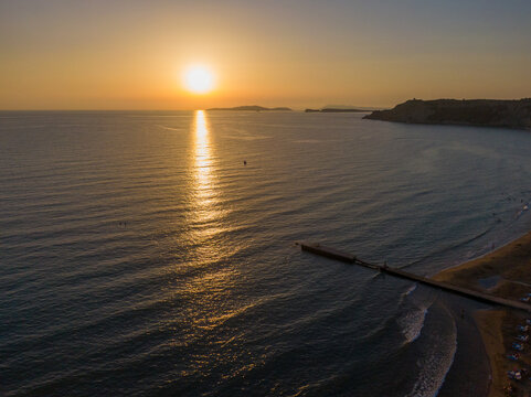 Golden sunset over calm ocean with pier