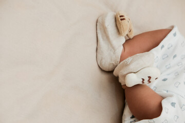 Baby sleep on brown bed. Feet in anti slip socks with fish shapes. Pastel color. Close Up.