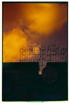 Colorful sunset behind barbed wire fence in urban area
