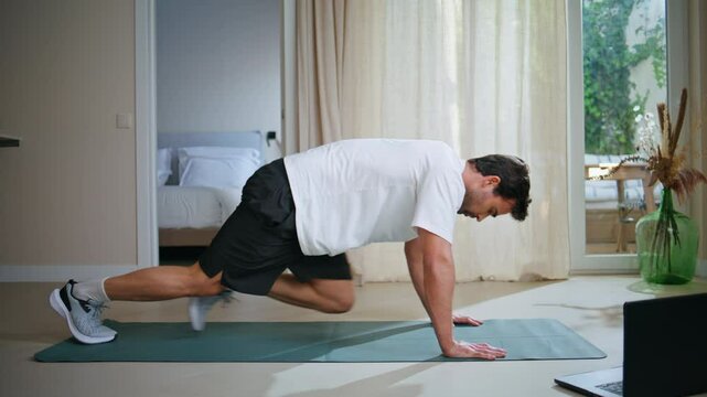Guy making sport exercises at daily workout at modern apartment. Athletic man