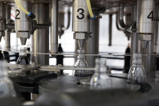 Bottling machine filling plastic bottles in a production line - Powered by Adobe