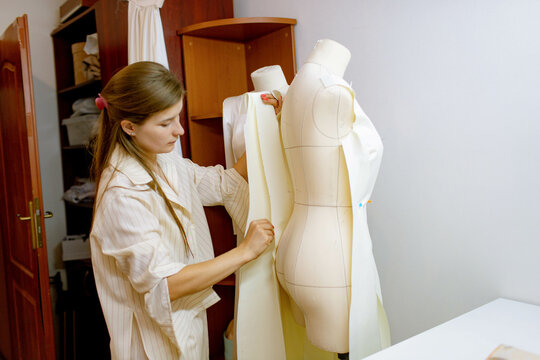a woman tries on a dress on a mannequin. 