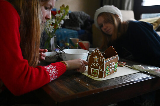 Two girls make a gingerbread house together