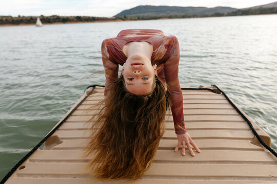 Slim woman doing yoga on pier