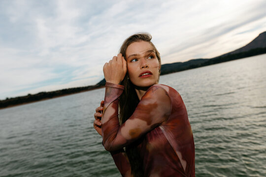 Calm young woman looking away near lake