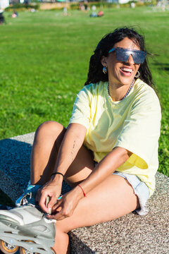 Happy woman with cool sunglasses putting on inline skates
