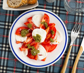 Service plate containing appetizing Caprese salad made of tomato and mozzarella with balsamic sauce