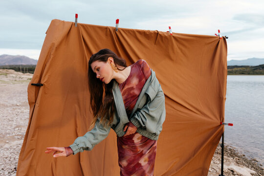Woman with stretched hand near brown curtain