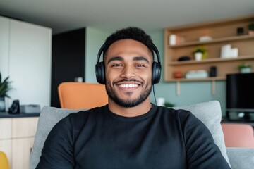 Fototapeta premium Portrait of a cheerful young man wearing headphones attending a video call, working remotely from his modern apartment