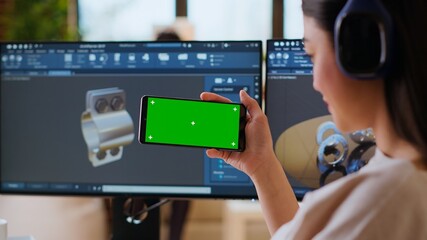 Software developer works in a modern office with green screen and dual monitors. Home workspace emphasizes industrial innovation and expertise in manufacturing design. Camera B.