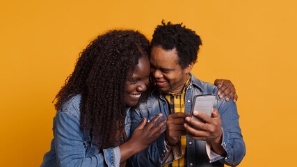 African american young couple having fun together with photos on smartphone, enjoying sweet moments with each other. Cute husband and wife take pictures on mobile phone. Camera A.