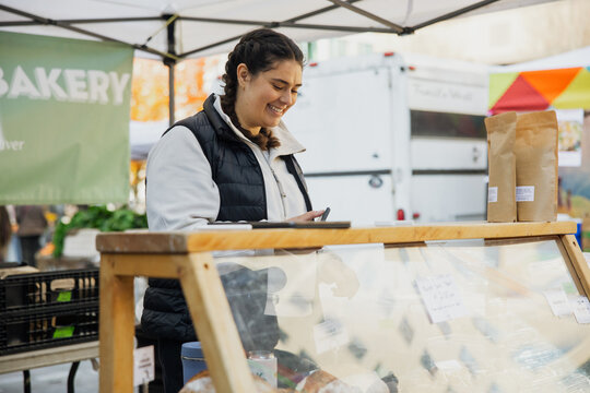 Smiling Vendor at Outdoor Bakery Market Stall With Fresh Goods