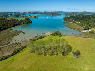 Aerial view of a tranquil bay with numerous sailboats. Green hills and meadows border the calm...