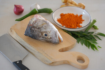 Fresh snapper fish on a wooden cutting board in a kitchen with a knife nearby