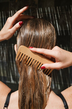 Woman with long hair using a wooden comb for grooming