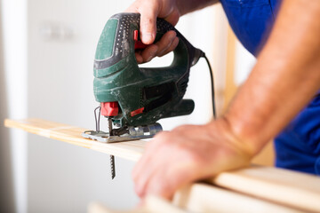 Work with an electric jigsaw - cutting a wooden board close-up