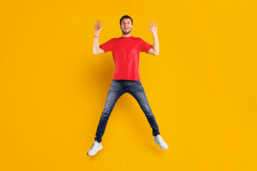 Expressing Joy And Happiness. Full length studio shot of active energetic young man jumping isolated over blue background. Excited bearded male model celebrating success or victory, copy space