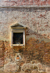 White window on old house wall Cracks in concrete visible red bricks.