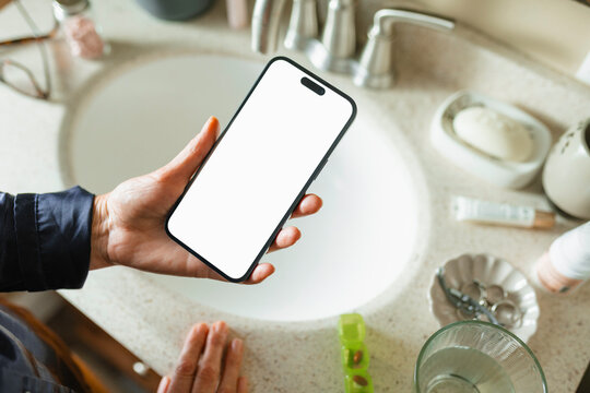  The woman uses a mobile phone with white screen and takes pills