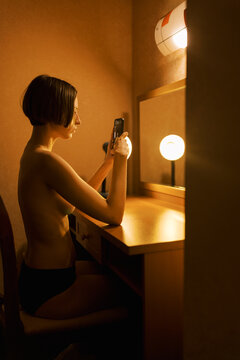 Portrait of androgyne person with cellphone reflecting in the mirror 