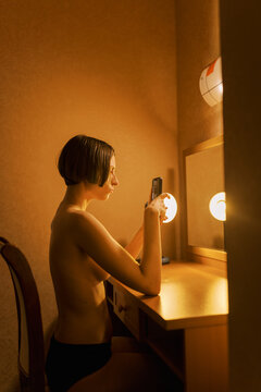 Portrait of androgyne person with cellphone reflecting in the mirror 