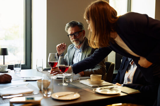 Waitress serves glass of wine to a guest