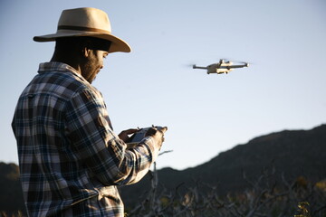 A drone pilot conducts a photograph survey of a farm.