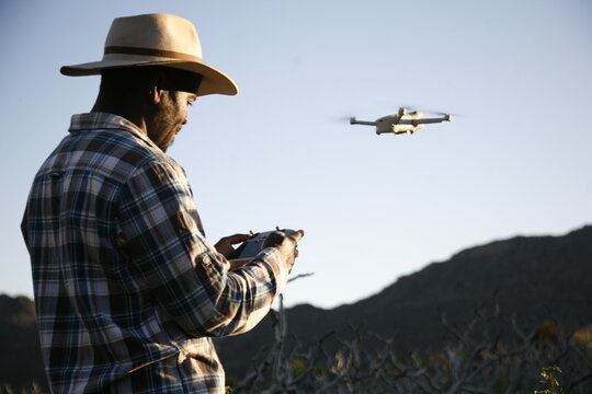 A drone pilot conducts a photograph survey of a farm.