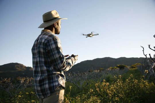 A farmer surveys land using drone photography. 