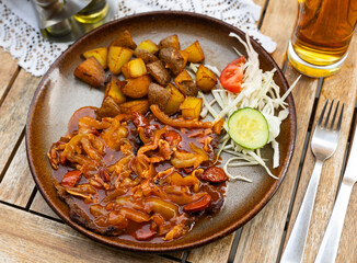 Traditional Slovak Tulacka rostenka, or Wanderer Roast Beef in sauteed tomato sauce with peppers, slices of smoked sausage and bacon, pared with baked potatoes, crisp coleslaw and glass of beer..