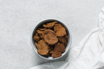 Overhead view of kuli-kuli in a white bowl, top view of nigerian groundnut cakes in a bowl, fresh homemade nigerian kulikuli in a ceramic bowl