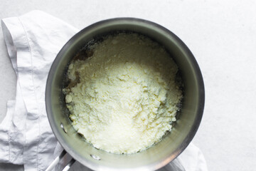 Overhead view of powdered milk in a saucepan, top view of full fat milk powder in a pot