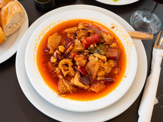 Spanish stew of chickpeas, pork, tomatoes with garlic and chorizo sausages. Traditional Catalan dish Callos con garbanzos on a white plate