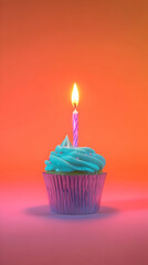Blue Frosted Cupcake with Lit Candle Sits Delightfully on a Vibrant Orange Backdrop