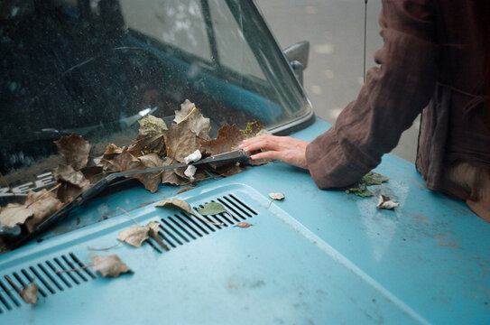 woman's hand on the hood of an old car