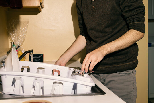 Young man washing dishes by hand in a kitchen