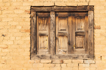 Khan Sahib Tehsil, Jammu and Kashmir, India. Wooden shuttered window in a yellow brick wall.