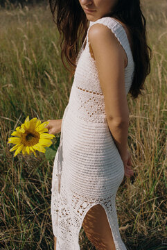 A girl in a crochet dress holding a sunflower