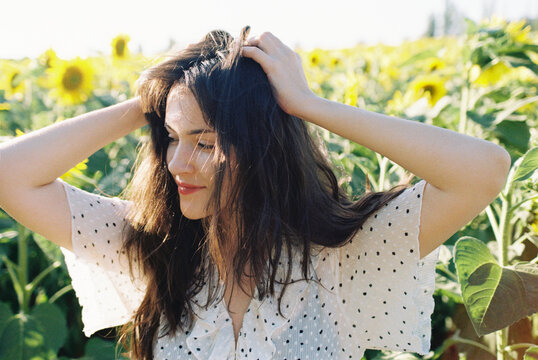 A smiley girl in a white dress posing amidst a sunflower field