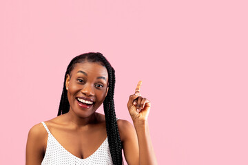 Young black lady in summer clothes pointing upwards on pink studio background. Millennial African American woman experiencing AHA moment, having creative idea, gesturing eureka