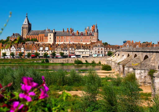 Scenic summer view of Gien townscape overlooking arched bridge across Loire river and medieval Chateau de Gien dominating over residential houses on sunny day, France