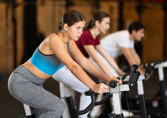 Athletic woman in top and leggings at cycling training. Client of the gym at a group workout on an...