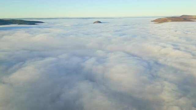 Aerial view of hills sticking up through a layer of low lying, thick fog