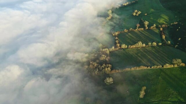 Downward aerial view of thick fog partially covering rural farmland in Wales
