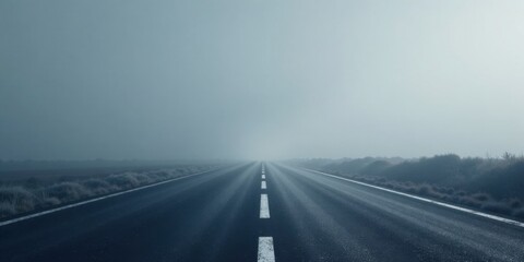 Fototapeta premium A long, straight highway disappears into a dense fog on a cold morning