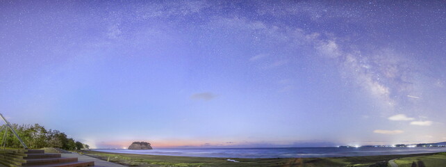 夜明けが近づく能登半島の海辺と天の川のパノラマ写真
