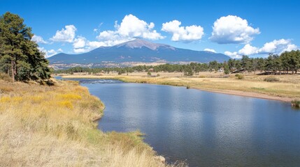 Obraz premium Serene River Landscape with Majestic Mountain View Under Blue Sky