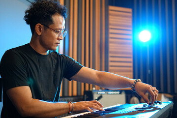 Musician playing music keyboard, Asian man in black shirt playing piano and practicing in home...